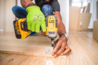 Sanisale - person-using-dewalt-cordless-impact-driver-on-brown-board